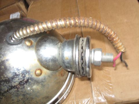 1990 Ford Bronco - Close-up of a chrome headlight assembly, showing a rusted protective conduit and exposed electrical wires.