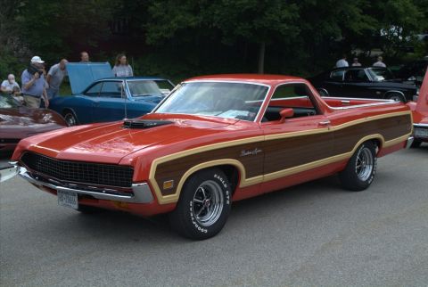 1970 Ford Ranchero - A classic red Ford Ranchero with wood grain trim is displayed at an outdoor car show.