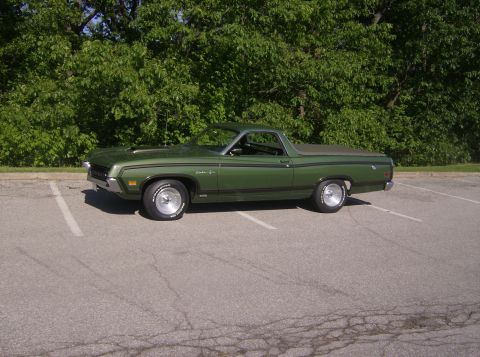 1970 Ford Ranchero - A green 1970 Ford Ranchero is parked in an outdoor lot with trees in the background.
