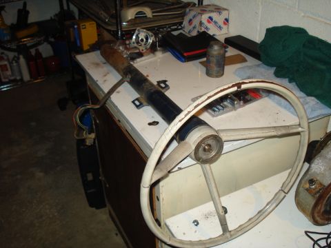 1967 Ford F-250 - Steering column and wheel assembly resting on a table, surrounded by other automotive parts.