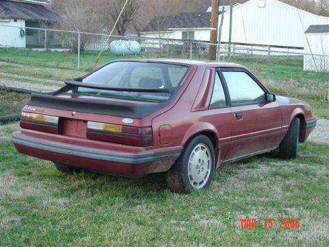 1984 Ford Mustang - This 1984 Ford Mustang coupe is seen from the rear three-quarter angle, parked on a grassy area.