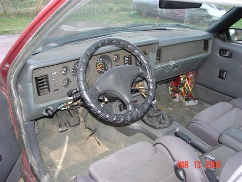 1984 Ford Mustang - Interior view of a 1984 Ford Mustang, exposed wiring and a manual transmission shifter.
