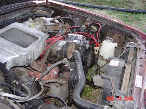 1984 Ford Mustang - The engine bay of a 1984 Ford Mustang shows its V8 engine with red spark plug wires and a metal air intake box.