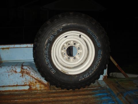 1967 Ford F-250 - A spare tire is mounted in the bed of a weathered blue pickup truck.