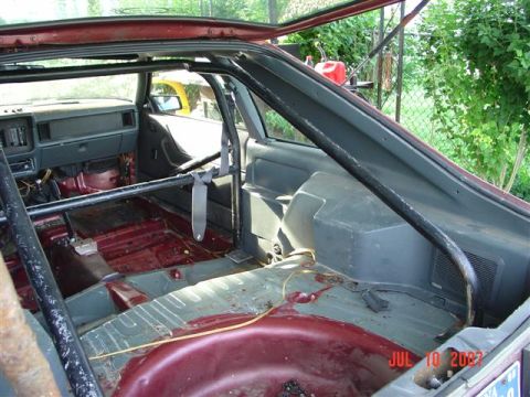 1984 Ford Mustang - The interior of a 1984 Ford Mustang shows a roll cage and a stripped-down cabin, indicating a focus on racing or performance modifications.