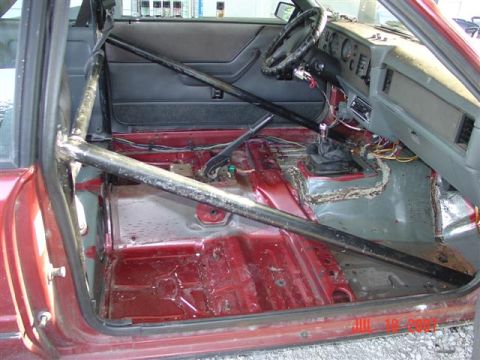 1984 Ford Mustang - Interior view of a 1984 Ford Mustang with a roll cage and stripped-down floor.