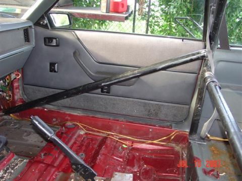1984 Ford Mustang - The interior of the vehicle shows a roll cage and exposed wiring, indicating modifications.