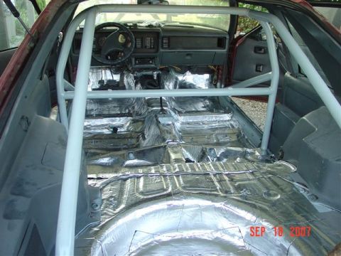 1984 Ford Mustang - The interior of a 1984 Ford Mustang shows a roll cage and sound deadening material installed on the floor.