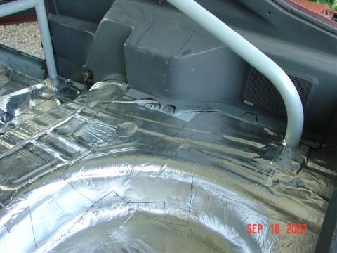 1984 Ford Mustang - The interior of a vehicle is being prepared for sound deadening installation, with a roll cage visible.