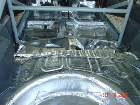 1984 Ford Mustang - The interior of a car is being prepared with sound deadening material, showing the floor and a roll cage.