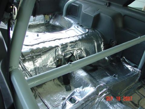 1984 Ford Mustang - The interior of a car is being prepped for sound deadening and has a roll cage installed.