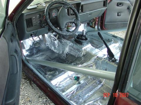 1984 Ford Mustang - The interior of a 1984 Ford Mustang shows a roll cage and sound deadening material covering the floor.
