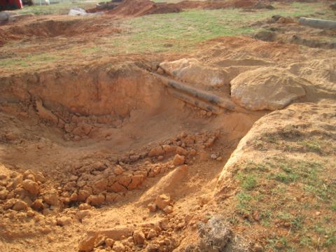 1996 Ford Bronco - A construction site shows exposed pipes running through a dug-out area with dirt mounds and grass.