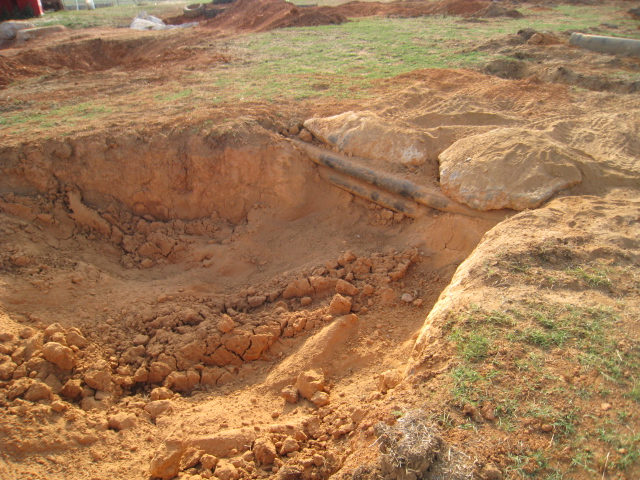 construction site with dirt mounds and exposed pipes