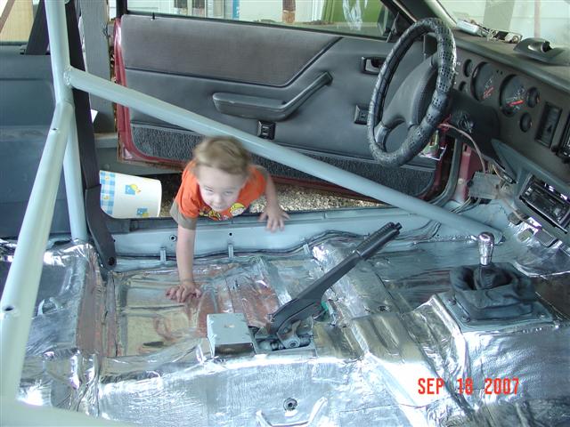1984 Ford Mustang interior with roll cage and child crawling
