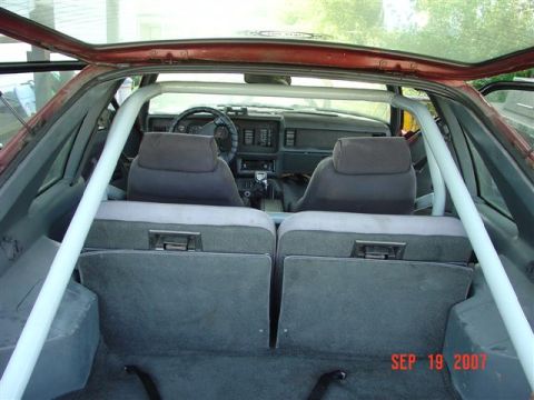 1984 Ford Mustang - Interior view of a 1984 Ford Mustang, showing the dashboard and seats with a roll cage installed.