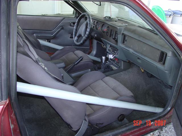 Interior of a 1984 Ford Mustang with racing seats and roll cage