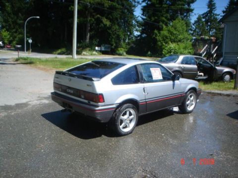 1990 Ford Bronco - This two-tone Honda CRX is parked outside on a sunny day with wet pavement.