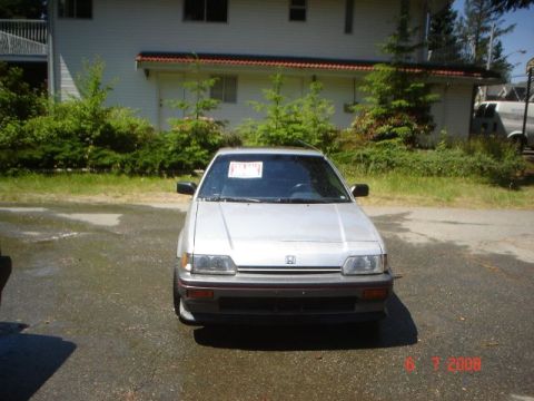 1990 Ford Bronco - This silver Honda Civic is parked on wet asphalt in front of a building.