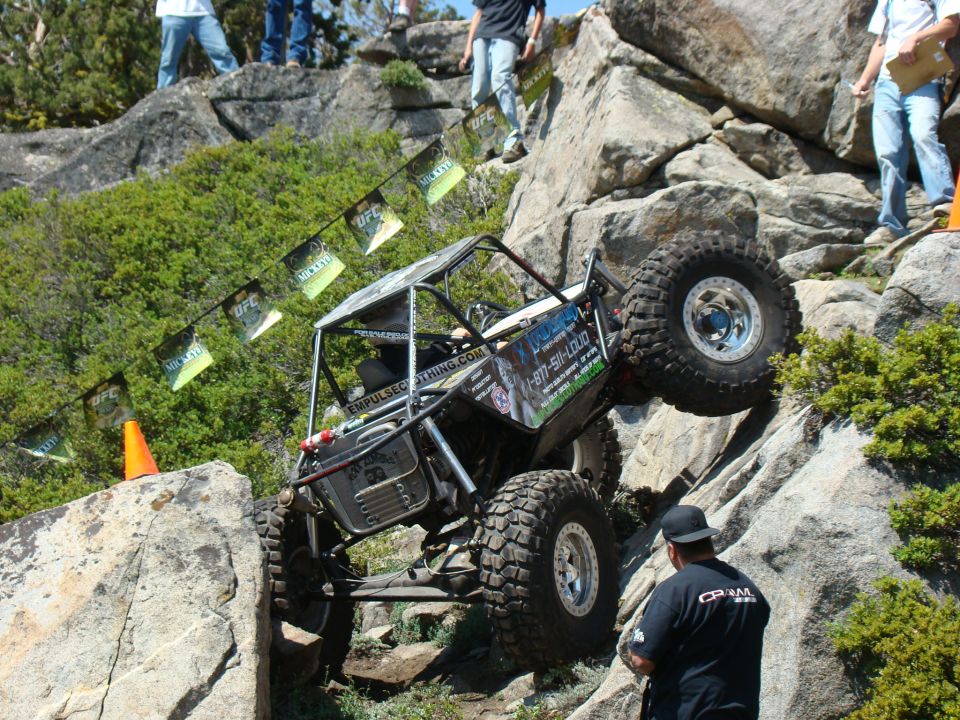 Custom off-road buggy climbing a rocky hill, with UFC and Mickey Thompson banners overhead.
