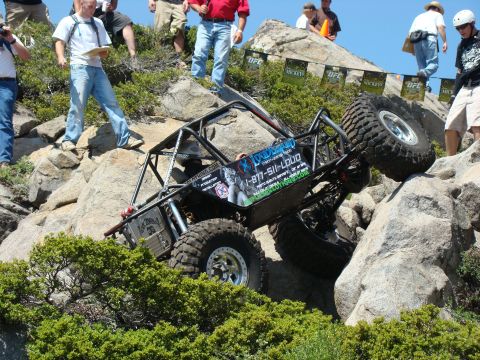 1989 Ford Bronco - A custom off-road buggy navigates a rocky incline during an event, with spectators watching from above.