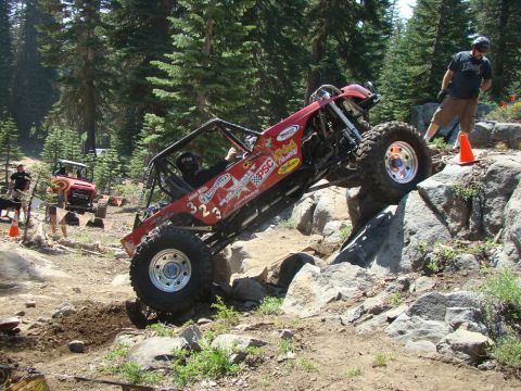 1989 Ford Bronco - An off-road buggy navigates a rocky incline, with another vehicle visible in the background on the trail.