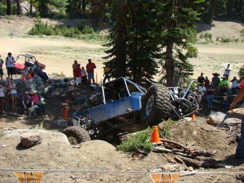 1989 Ford Bronco - A group of people gather around a blue SUV in an outdoor setting.