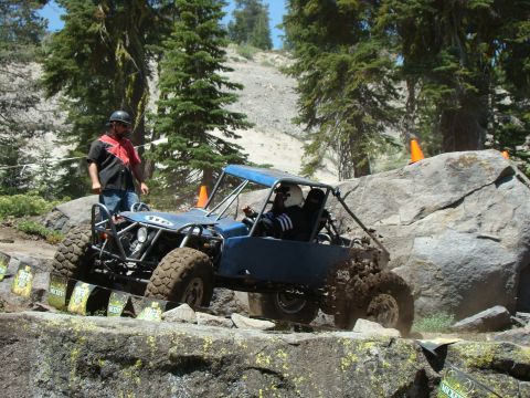 1989 Ford Bronco - A blue buggy navigates a rocky obstacle course with a spotter watching.