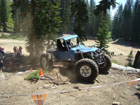 1989 Ford Bronco - A modified off-road buggy navigates a challenging dirt course with spectators in the background.