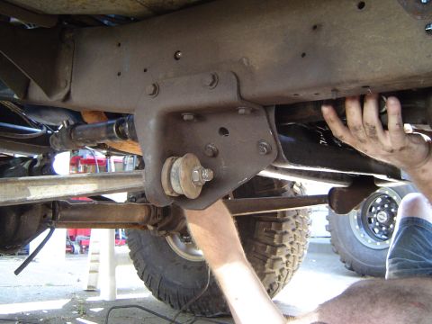 1979 Ford Bronco - Mechanic working on the undercarriage of a large truck, focusing on suspension parts.