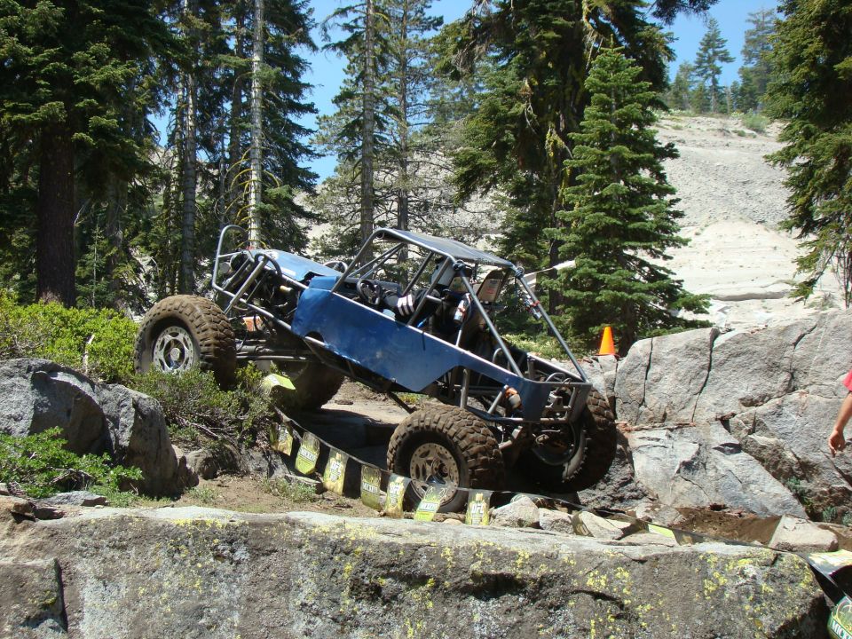 Blue custom off-road buggy with roll cage navigating a rocky trail