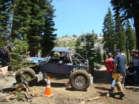1989 Ford Bronco - A custom-built off-road vehicle navigates a rocky trail surrounded by trees and spectators.