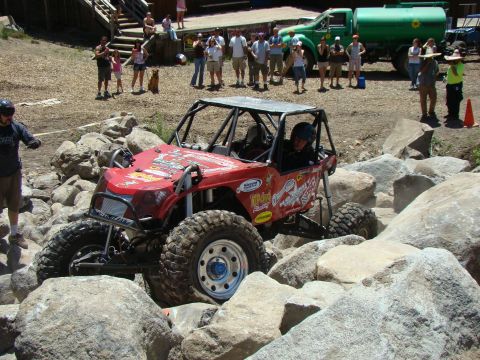 1989 Ford Bronco - A custom-built off-road buggy tackles a rocky course with spectators watching.