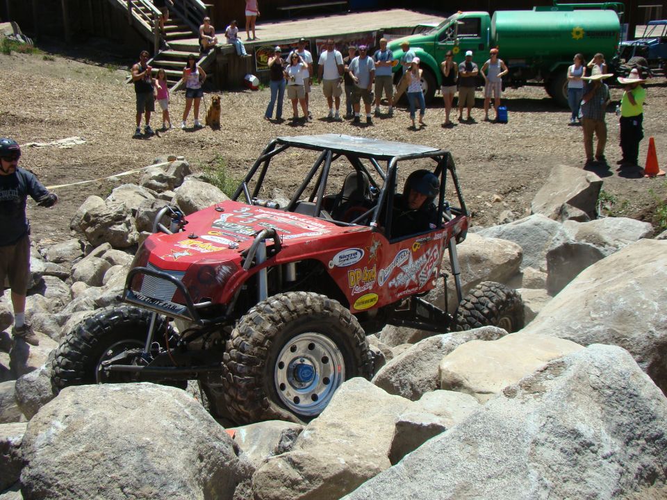 Red off-road buggy with roll cage navigating large rocks