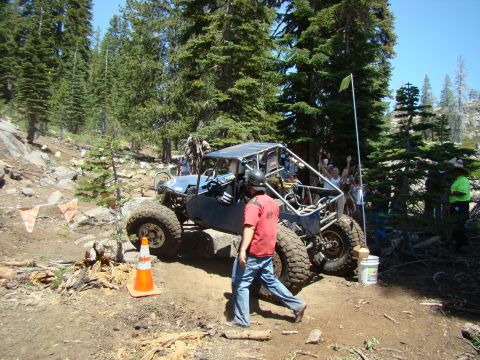 1989 Ford Bronco - A custom-built off-road buggy navigates a rocky trail with onlookers watching.