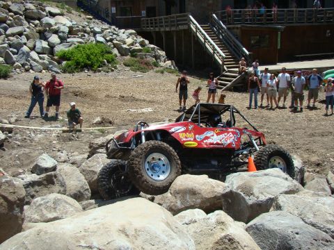 1989 Ford Bronco - A custom-built buggy tackles a rocky obstacle course with spectators watching.