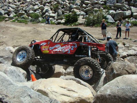 1989 Ford Bronco - This custom buggy is tackling a challenging rock crawling course with spectators watching.