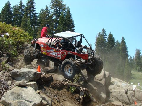 1989 Ford Bronco - A heavily modified off-road buggy navigates a challenging rocky terrain during an event.