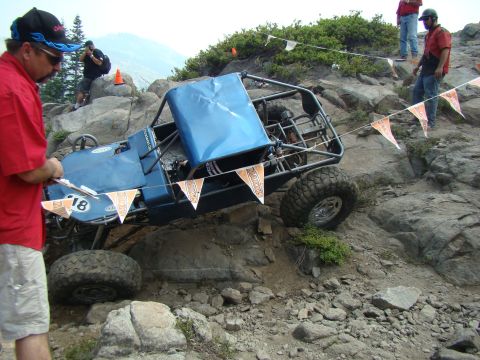 1989 Ford Bronco - An off-road buggy navigates a challenging rocky course, marked by orange pennant flags.