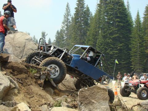 1989 Ford Bronco - An off-road buggy navigates a difficult rocky terrain with spectators watching.