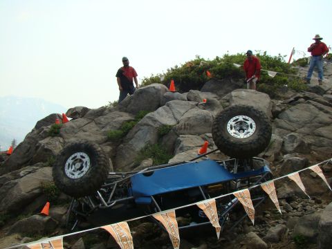 1989 Ford Bronco - Off-road buggy competition scene with vehicle overturned on rocky terrain.
