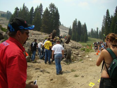 1989 Ford Bronco - Spectators watch as an off-road vehicle gets stuck on a rocky incline during an event.