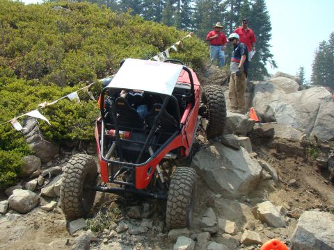 1989 Ford Bronco - A heavily modified off-road buggy tackles a challenging rocky terrain during an event.