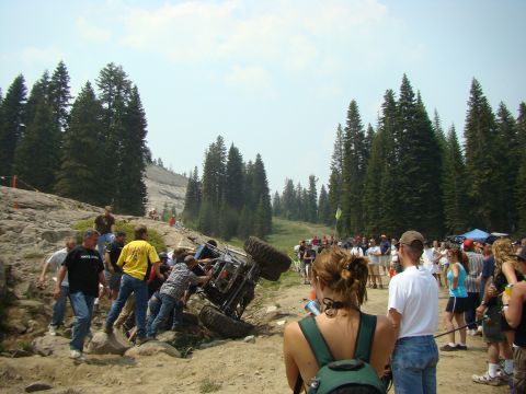 1989 Ford Bronco - Off-road vehicle stuck on rocky terrain, with spectators gathered around.
