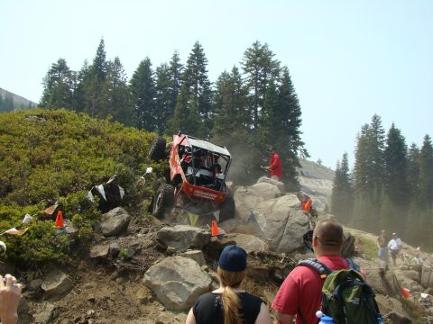 1989 Ford Bronco - An off-road buggy navigates a challenging rocky terrain during an event, with spectators observing the difficult climb.