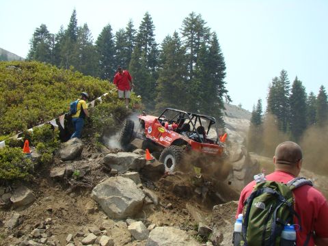 1989 Ford Bronco - An off-road buggy navigates a challenging rocky incline during an event, kicking up dust.
