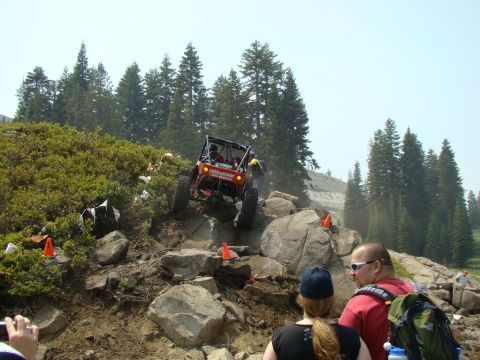 1989 Ford Bronco - An off-road buggy navigates a rocky incline during an event, with spectators observing the challenging terrain.