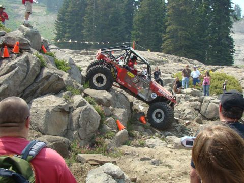 1989 Ford Bronco - A custom-built off-road buggy tackles a challenging rocky terrain during an event, with spectators watching from the sidelines.