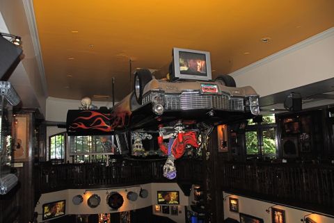 1996 Ford Bronco - A vintage car is suspended upside down from the ceiling, decorated with flames and a television screen.