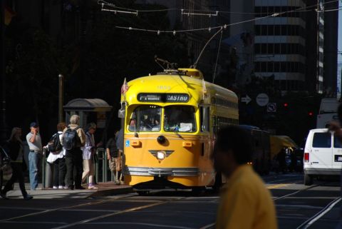 1996 Ford Bronco - A yellow streetcar is stopped at a streetcar stop with passengers waiting. A white van is visible in the background.